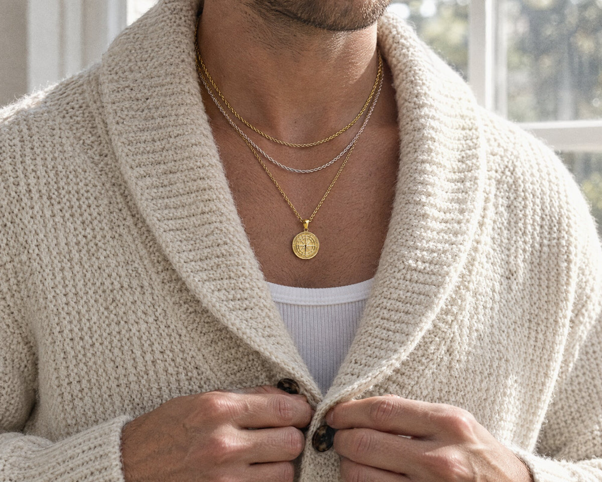 A man wearing a silver Mini Medusa pendant on a London street at night, and a man layering chains and a compass pendant