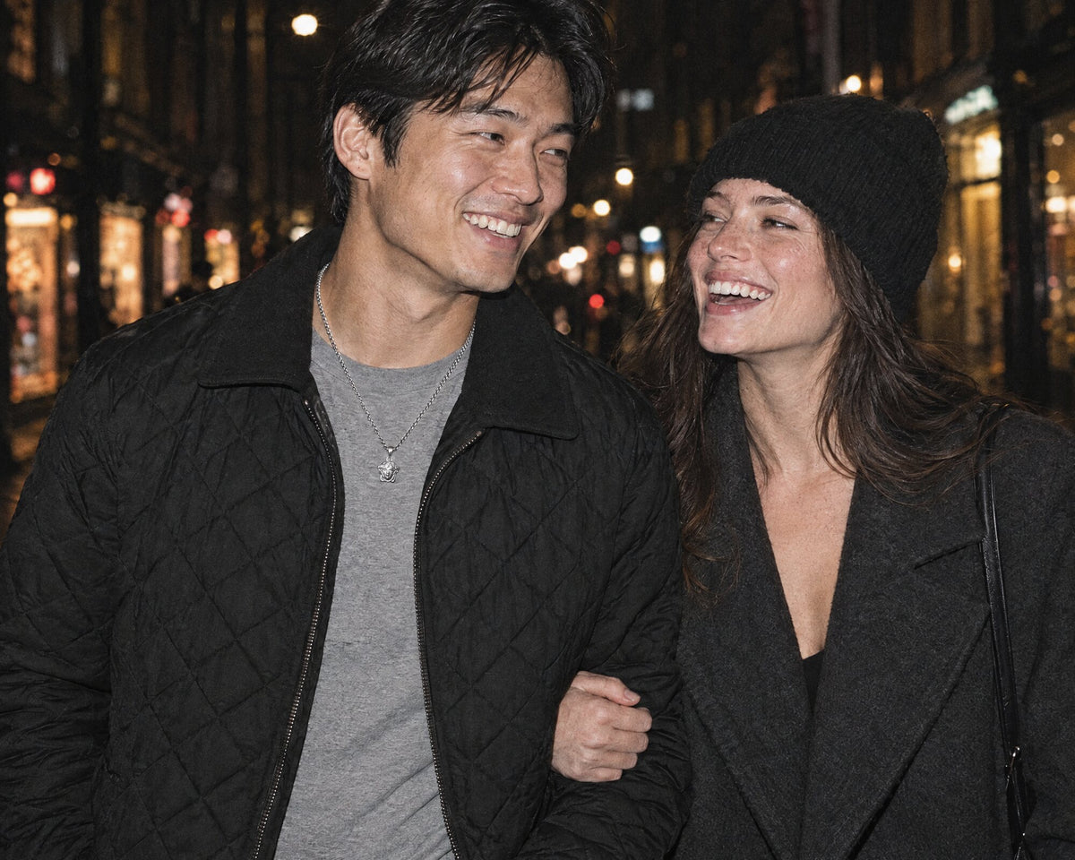 A man wearing a silver Mini Medusa pendant on a London street at night, and a man layering chains and a compass pendant